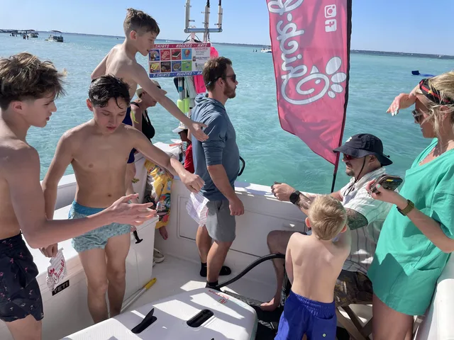 Guests buying snacks and gear from a floating vendor boat at Crab Island in Destin