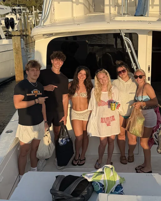 A group of friends smiling together on a Destin charter boat at the dock during golden hour