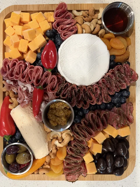 An overhead view of a charcuterie board with cheeses, cured meats, olives, and dried fruit served aboard a Destin charter
