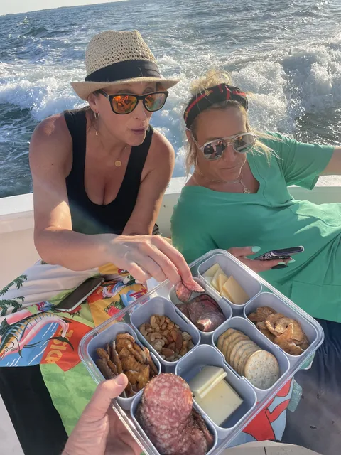 Guests enjoying a charcuterie snack tray aboard a Destin charter with the wake behind them