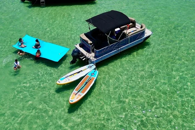Aerial view of a Destin Crab Island pontoon charter with paddleboards and a floating mat in the shallow green water