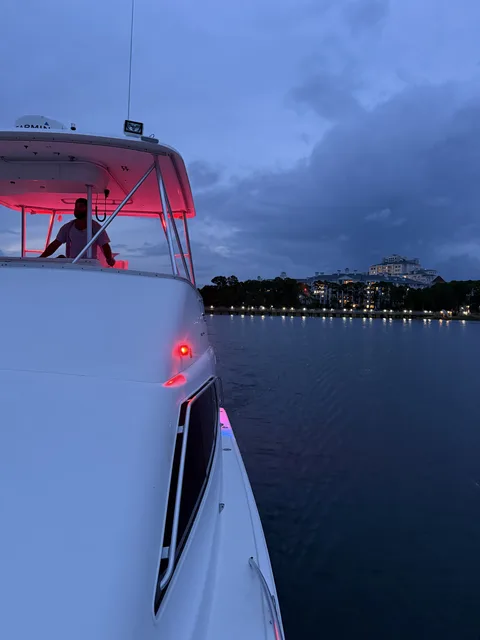 Charter boat cruising past the lit-up Sandestin waterfront near Destin at dusk